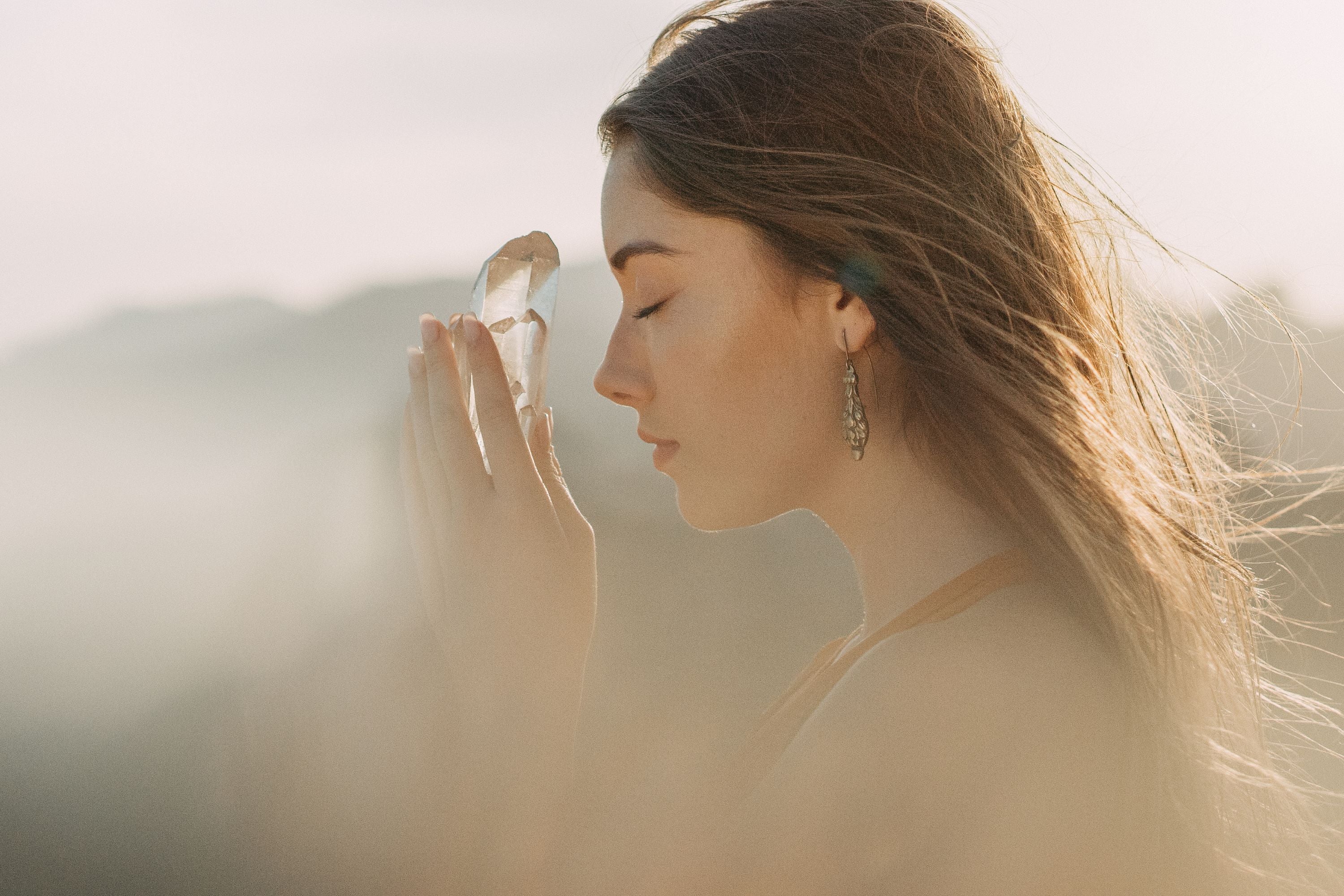 Femme fermant les yeux tenant une pierre naturel entre ses mains et proche de son vigie