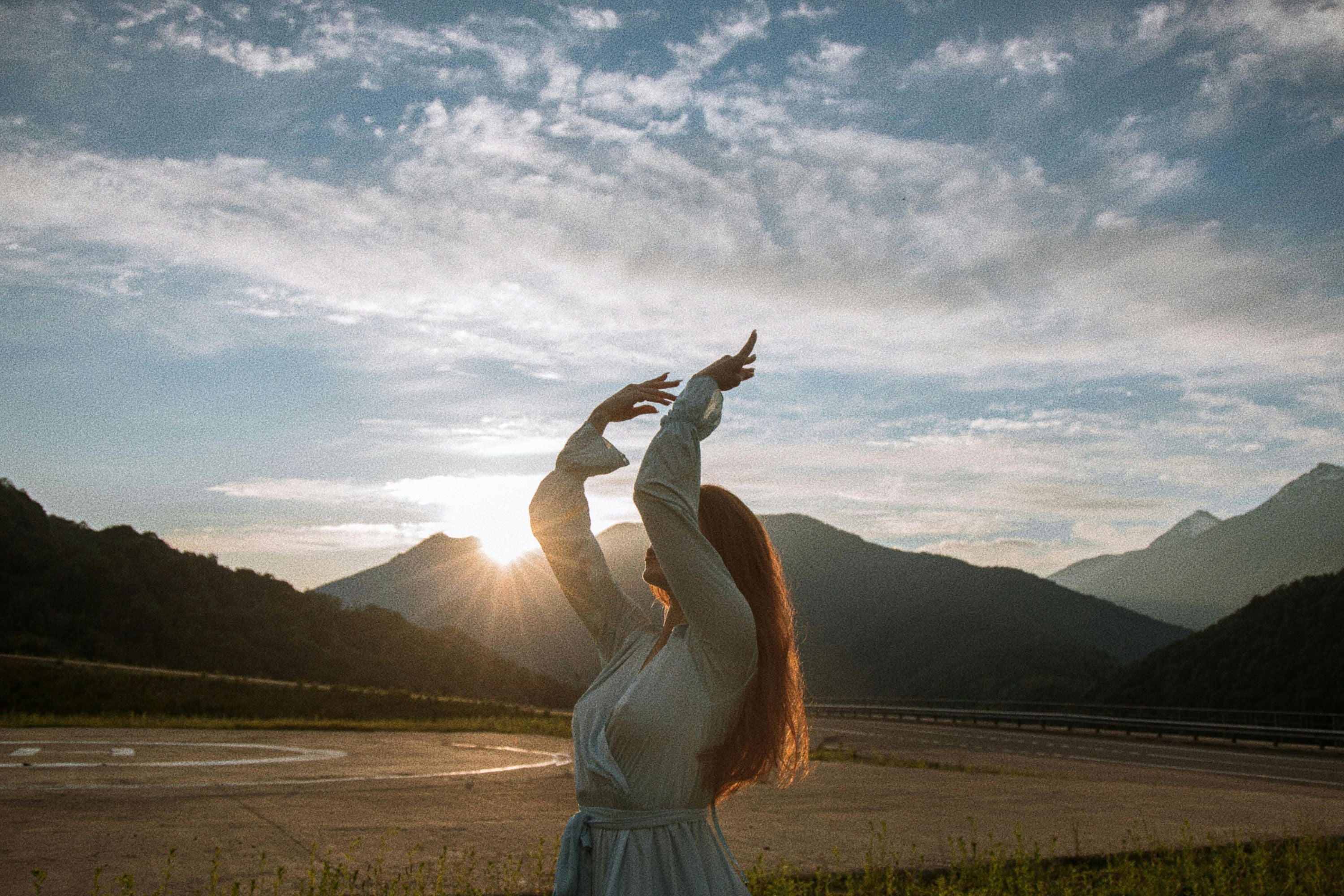Femme debout devant des montagnes et levant les bras vers le ciel