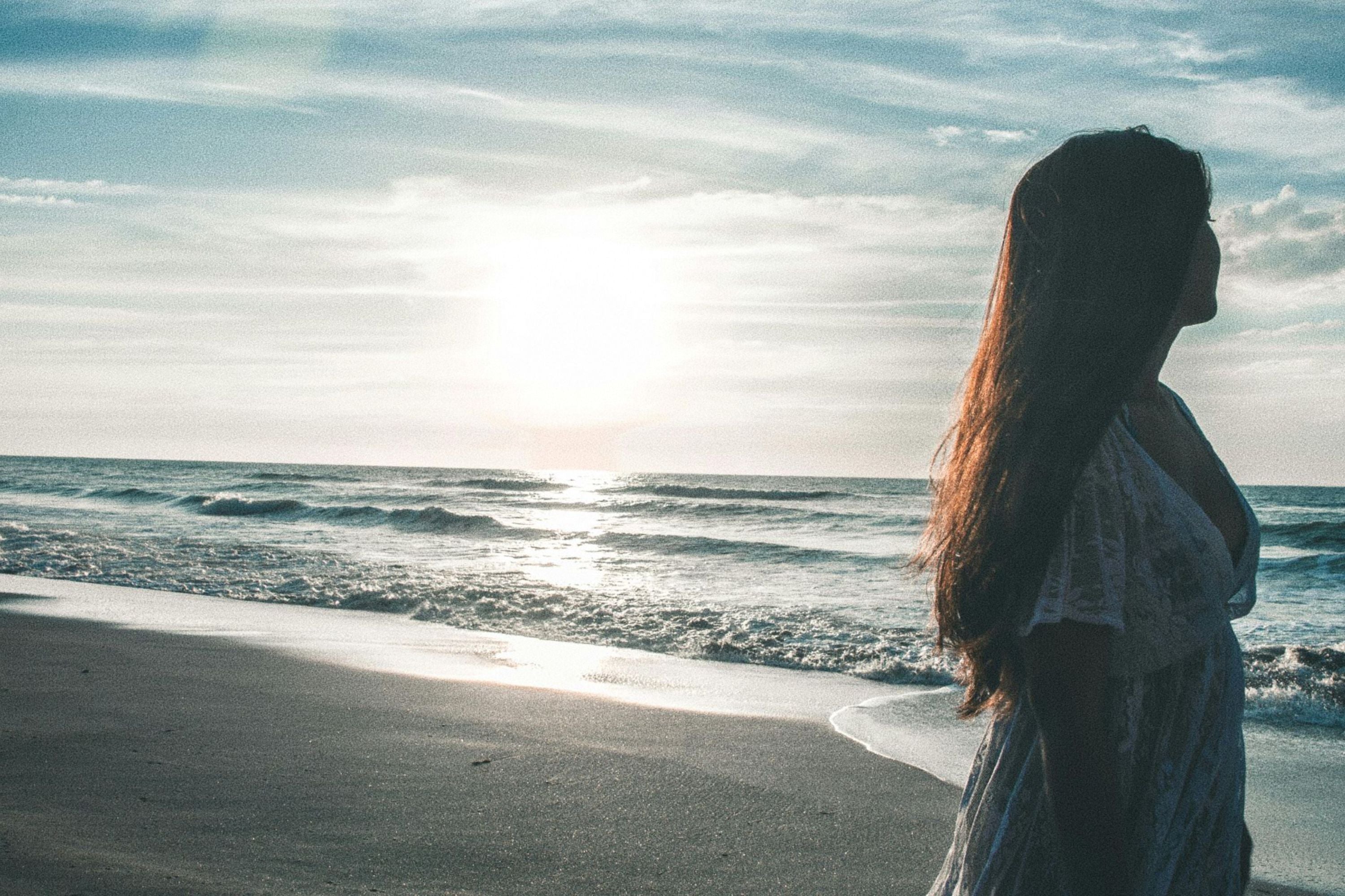 Femme debout devant la mer regardant au large