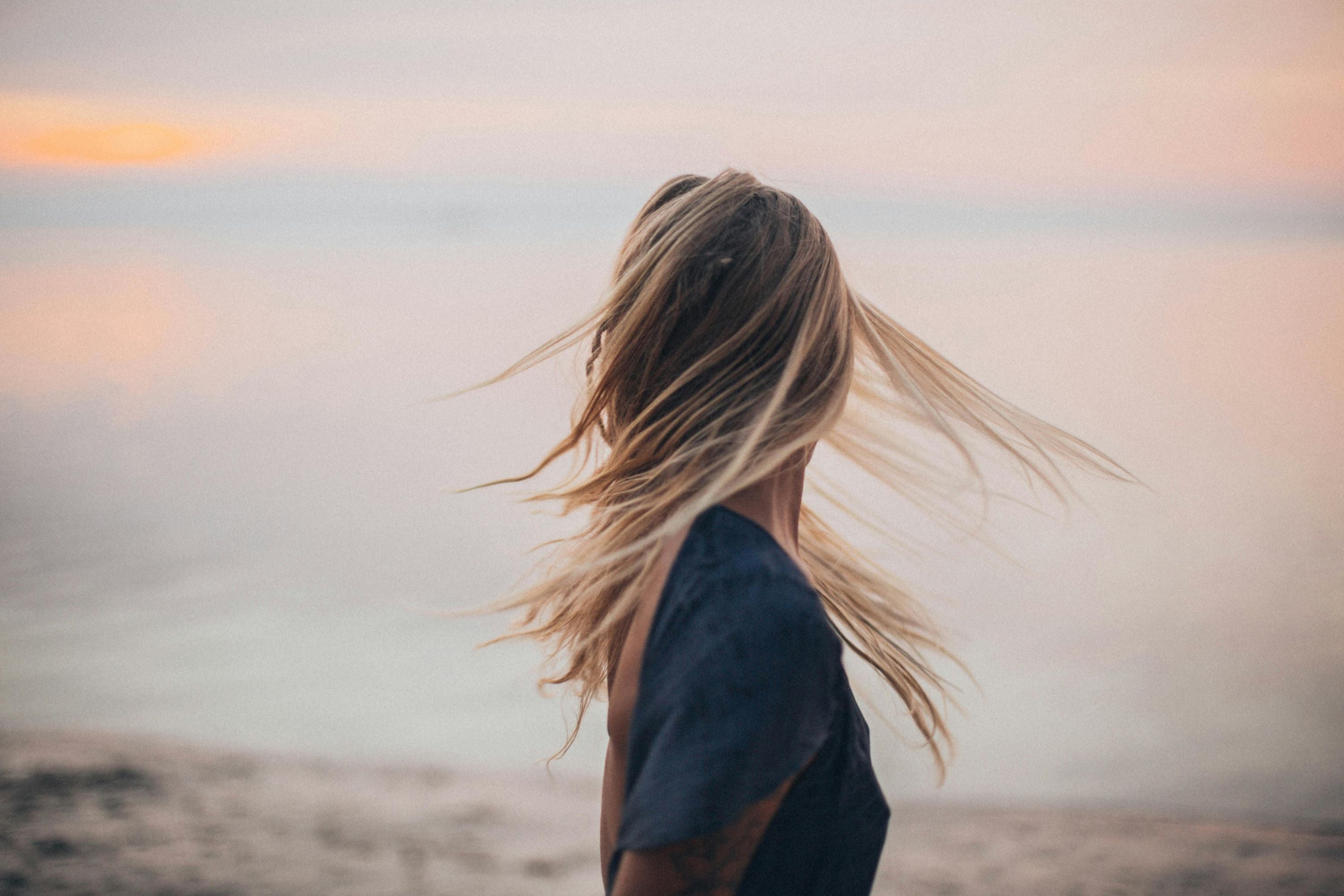 Femme de dos face à la mer pendant un coucher de soleil